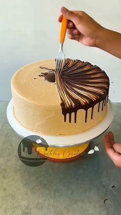 someone is decorating a cake with chocolate icing on the top and holding a fork