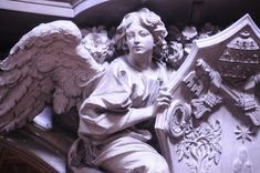 an angel statue sitting on top of a building next to a shield and coat of arms