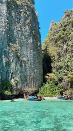 people in boats on the water near large cliffs