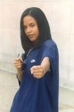 a woman with long black hair pointing at something in her hand while wearing a blue dress