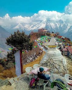 a person sitting at a table on top of a hill with mountains in the background