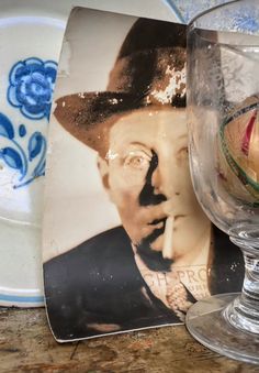 a glass with an image of a man in a hat on it next to a plate