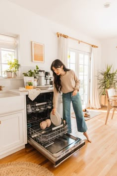 a woman standing in front of an open dishwasher