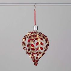 a glass ornament hanging from a metal bar with red and gold decorations on it