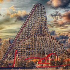 a large roller coaster in the middle of a body of water under a cloudy sky