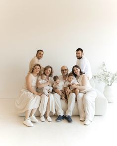 a group of people sitting on top of a white couch in front of a wall