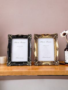 two frames sitting on top of a wooden table next to a vase with flowers in it