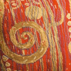 an orange and gold pillow with decorative designs on it's side, close up