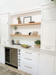 a kitchen with white cabinets and open shelving above the dishwasher is shown