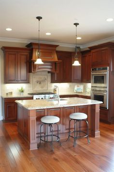 two stools sit at the center of a kitchen island in front of an oven