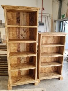 two wooden bookshelves sitting next to each other in a room filled with wood pallets