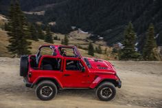 a red jeep driving down a dirt road