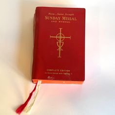 a red book sitting on top of a white table next to a tassell