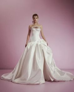 a woman in a white wedding dress standing on a pink background