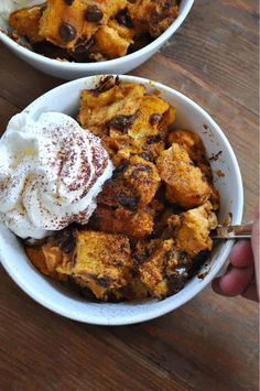 two white bowls filled with food on top of a wooden table