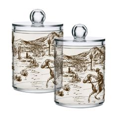 two glass canisters with horses and mountains in the background, one has a lid