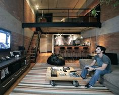 a man sitting on a couch in front of a flat screen tv next to a coffee table