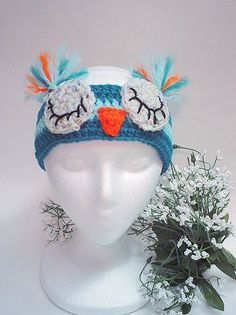 a white mannequin head wearing a blue and orange hat with two birds on it