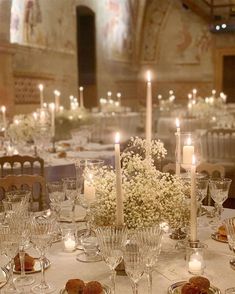 a table set up with candles, plates and flowers on it for a formal function