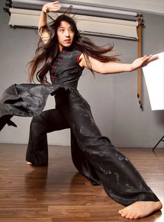 a woman is dancing on the floor with her hands in the air and she has long black hair