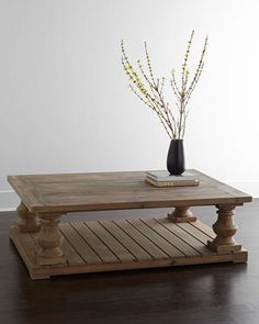 a wooden table with a vase on top and some flowers in the middle, sitting on a hard wood floor