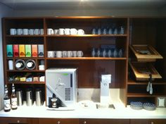 a coffee machine sitting on top of a counter next to a shelf filled with cups