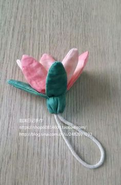 a pink and green flower on top of a wooden table next to a white cord