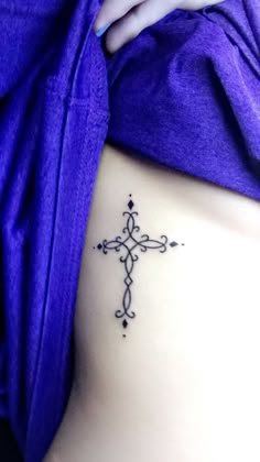 a cross tattoo on the side of a woman's stomach