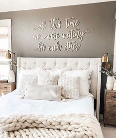 a white bed sitting under a metal wall sign