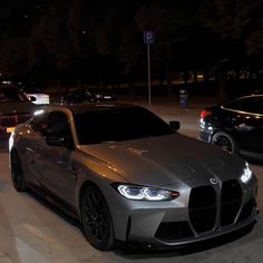 two cars parked next to each other in a parking lot at night with lights on