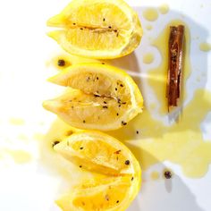 sliced up lemons on a white plate with mustard and cinnamon sticks next to them