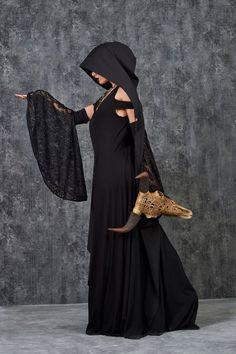 a woman in a black dress with a veil on her head is holding a purse