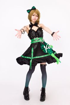 a woman dressed in black and green is posing for the camera with her hands out