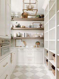 a kitchen with white cabinets and shelves filled with dishes