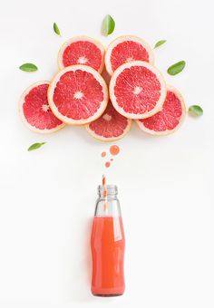 grapefruit and orange juice in a glass bottle with leaves coming out from the top