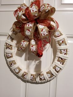 a christmas wreath hanging on the front door with red and white bows, decorated with gingerbreads