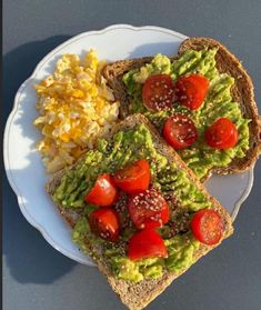 two slices of toast with avocado, tomatoes and other toppings