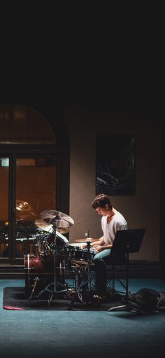 a man sitting in front of a drum set