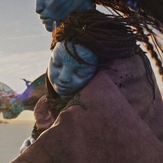 two people with blue face paint and braids on their heads, one is hugging the other