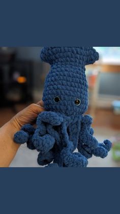 a crocheted blue octopus stuffed animal being held by a person's hand