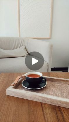 a cup of tea sitting on top of a wooden tray next to a white couch