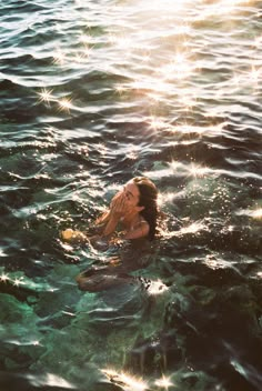 a woman floating in the water with her hands to her face