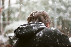 a person standing in the snow with their back to the camera, looking at something