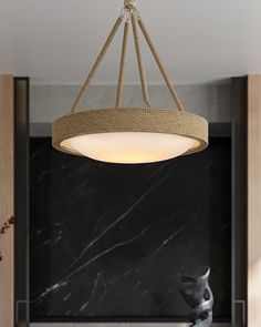 a modern chandelier hanging from the ceiling in a kitchen with marble counter tops