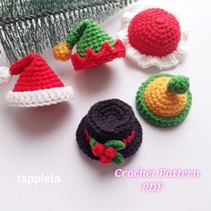 crochet christmas hats and ornaments are displayed on a white surface next to a pine tree