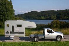 a truck towing a camper parked next to a lake