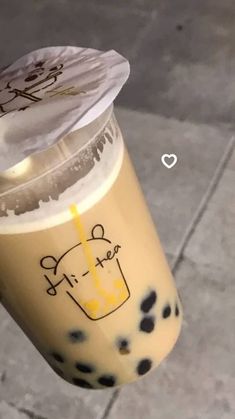 an iced drink with black spots on the bottom and yellow liquid in its plastic cup