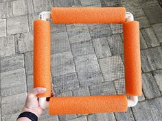 a person holding an orange piece of furniture on top of a brick flooring area