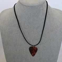 a necklace on a mannequin with a red heart shaped pendant hanging from it