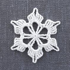 a white crocheted snowflake on a gray surface